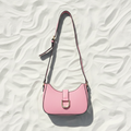 Borsa rosa con bordi neri flat lay su sabbia